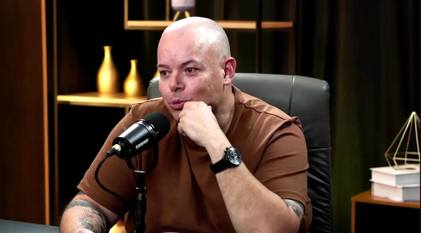 Cristian Trentin ouvindo com a mão no queixo durante a gravação do podcast Continue Jogando